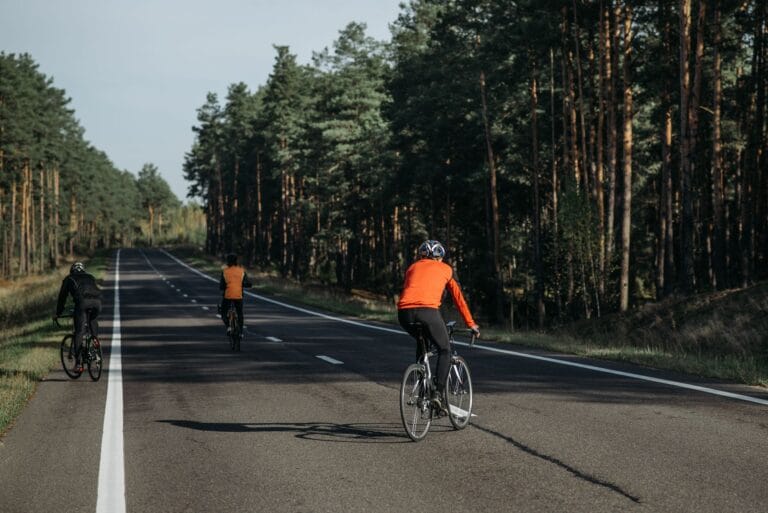 Grupa rowerzystów na malowniczej leśnej trasie w słoneczny dzień